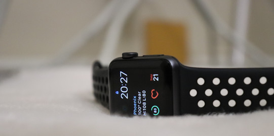Foto zeigt eine schwarze Smartwatch auf weißem, plüschigem Untergrund